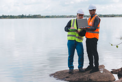 Rear view of man standing by lake