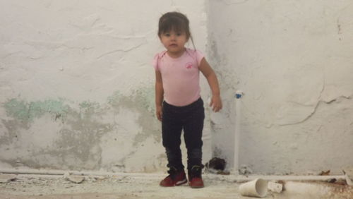 Portrait of cute girl standing against wall