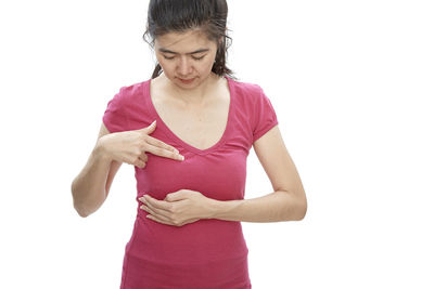 Woman touching breast while standing against white background