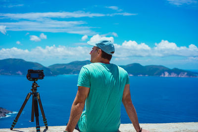 Rear view of man photographing sea against sky