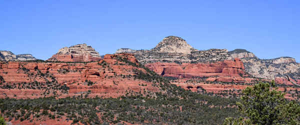 Rock formations on landscape against clear blue sky