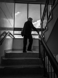 Rear view full length of woman moving up on steps in building