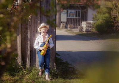 Boy playing guitar while standing outdoors