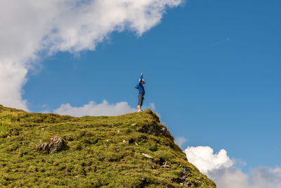 Low angle view of boy standing at the edge of mountain against sky