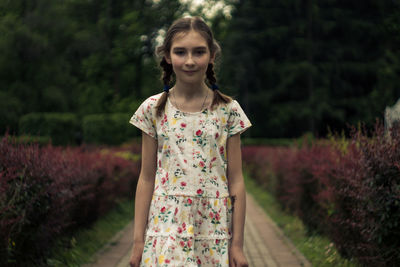 Portrait of young woman standing against trees