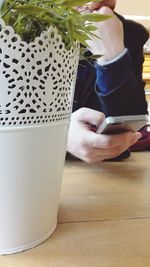Low section of woman holding smart phone at home