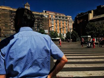 Rear view of woman walking against buildings in city