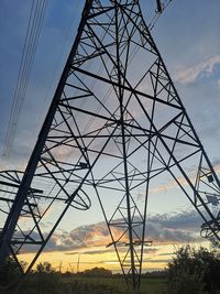 Low angle view of electricity pylon against sky during sunset