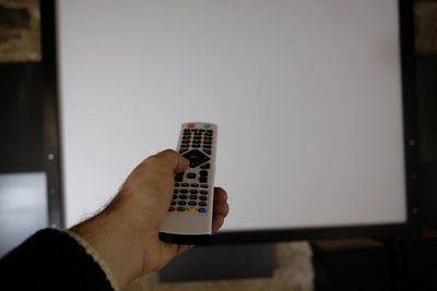 Cropped hand of man using remote at home