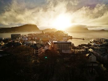 Town by sea against sky during sunset