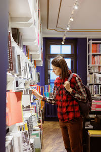 Side view of woman standing in library