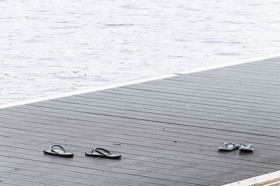 High angle view of slippers on sidewalk by sea