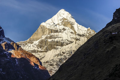 Low angle view of snowcapped mountains against sky