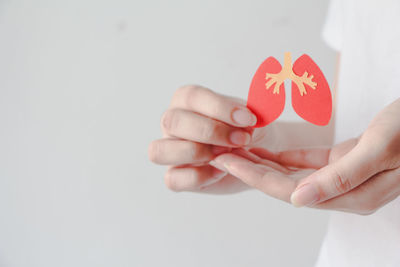 Cropped hand holding heart shape against white background