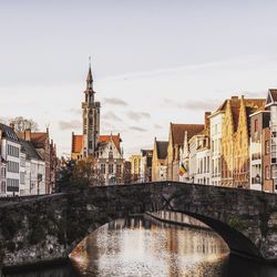 Bridge over river in city against sky