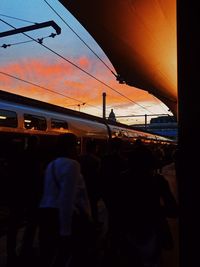 People waiting at airplane against sky during sunset