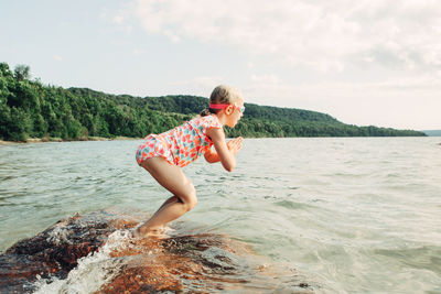 Side view of girl jumping in river