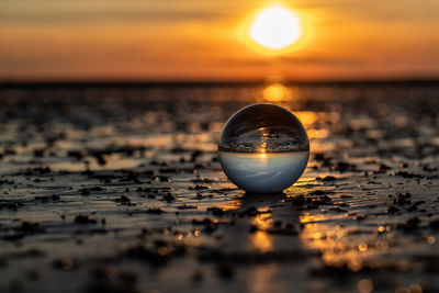 Close-up of crystal ball against sky during sunset