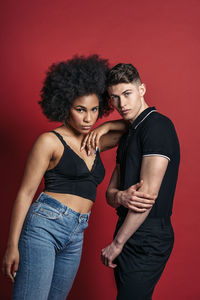 Stylish diverse girlfriend and boyfriend posing in a studio shooting with red background