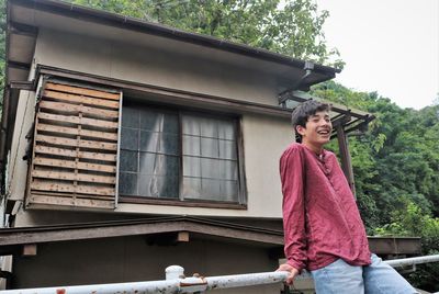 Portrait of smiling teenage boy standing against crumbling building