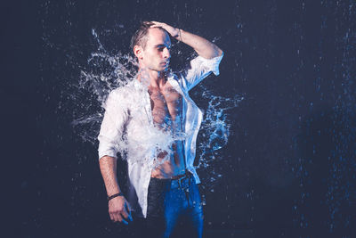 Portrait of young man looking away against black background