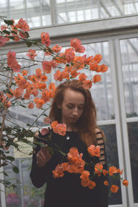 Close-up of young woman with flowers in window