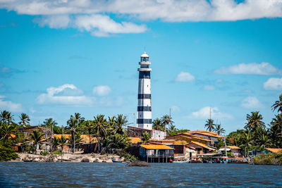 Lighthouse by sea against sky