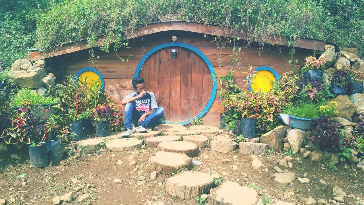 YOUNG WOMAN STANDING BY PLANTS