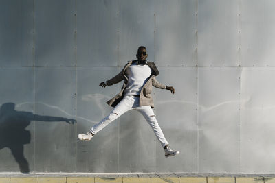 Man jumping by metallic wall