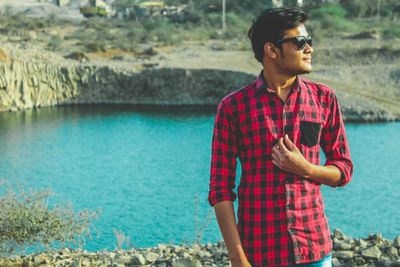 Young man standing by lake