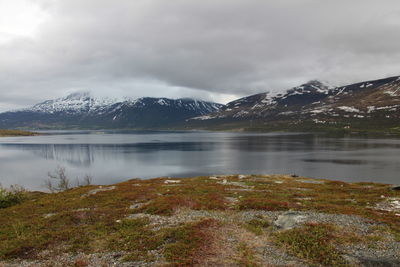 Scenic view of lake and mountains against cloudy sky