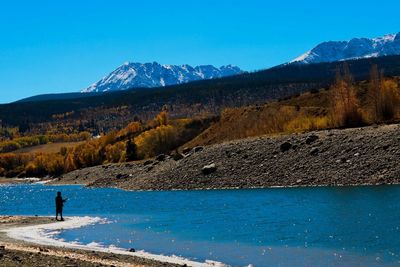 Rear view of road in front of mountains against clear blue sky