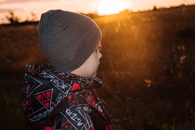 Portrait of girl standing on field against sky during sunset