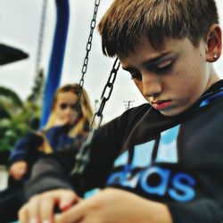 Close-up of boy playing on swing