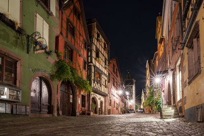 Illuminated alley amidst buildings in city at night