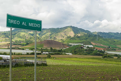 Information sign on field against cloudy sky