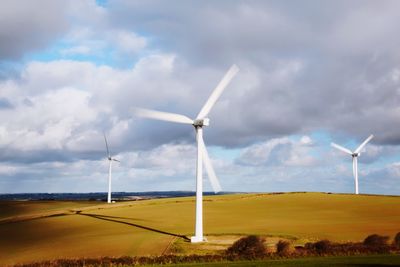 Windmills on field against sky