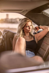 Beautiful woman looking away while sitting at car