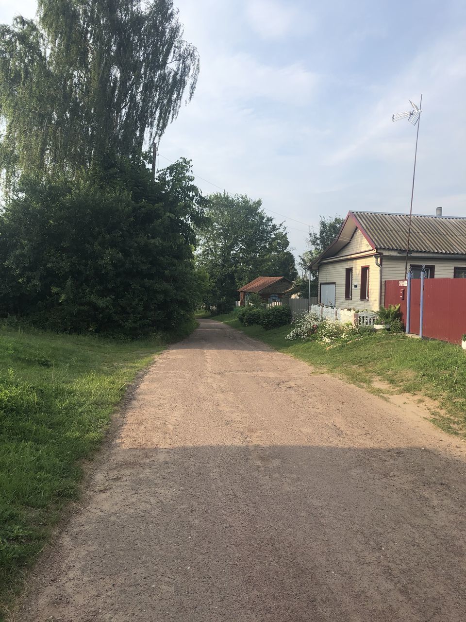 ROAD AMIDST BUILDINGS AND TREES AGAINST SKY