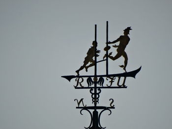 Low angle view of weather vane against clear sky