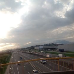 Road passing through highway against cloudy sky