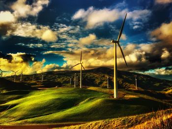 Wind turbines on field against sky