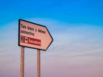 Low angle view of road sign against blue sky