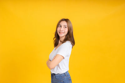 Portrait of a smiling young woman against yellow background