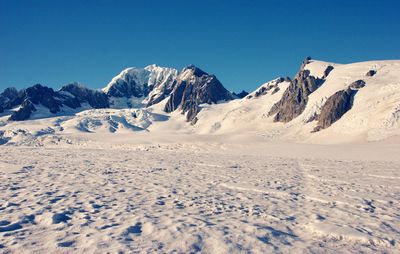 Scenic view of snowcapped mountains against clear blue sky