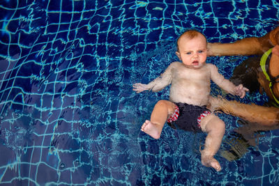 Little boy swimming in pool with parent