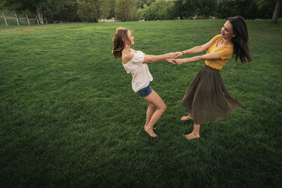 Side view of lesbian couple playing on grassy land