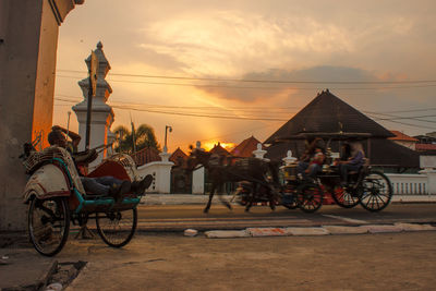 People in horse cart on road during sunset