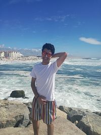 Young man standing on rock at beach 