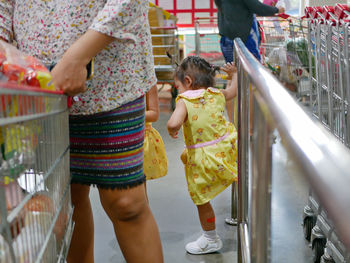 Midsection of mother with daughter at supermarket